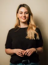 Xenia Rösch, Halbportrait, lächelnd, Blick in Kamera, neutraler Hintergrund