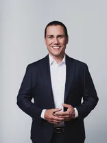 Thorsten Schwarz, Halbportrait, lächelnd, Blick in Kamera, neutraler Hintergrund