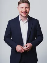 Nico Gunzelmann, Halbportrait, lächelnd, Blick in Kamera, neutraler Hintergrund